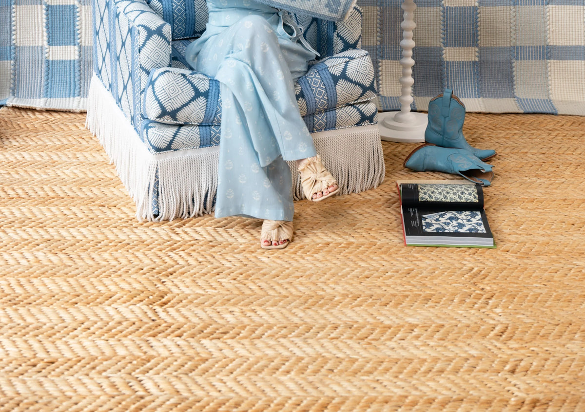 Natural tan jute herringbone area rug styled in a light blue coastal-inspired room
