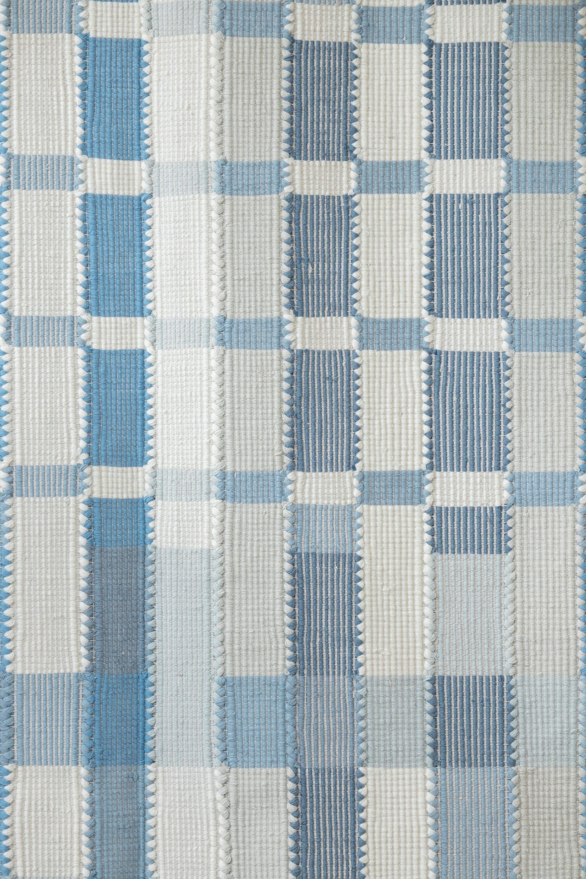 Blue and ivory geometric plaid flatweave rug showing repeating vertical and horizontal woven blocks