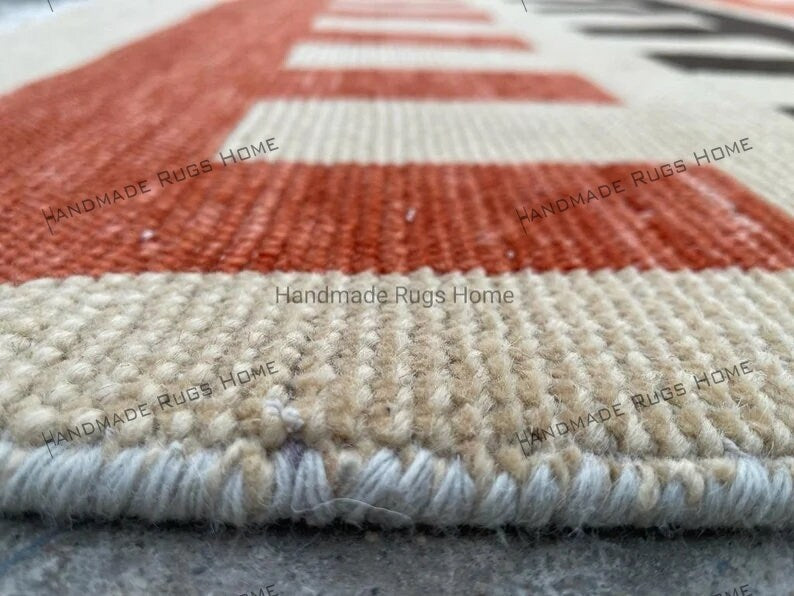 Handmade kilim rug with intricate block designs in red, black, and beige.