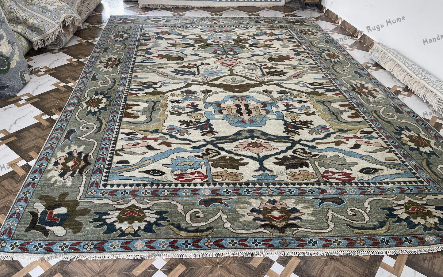 Handwoven Turkish Oushak rug featuring an ivory base with intricate blue, olive, and floral motifs, bordered by traditional patterns, perfect for adding elegance to any home decor.