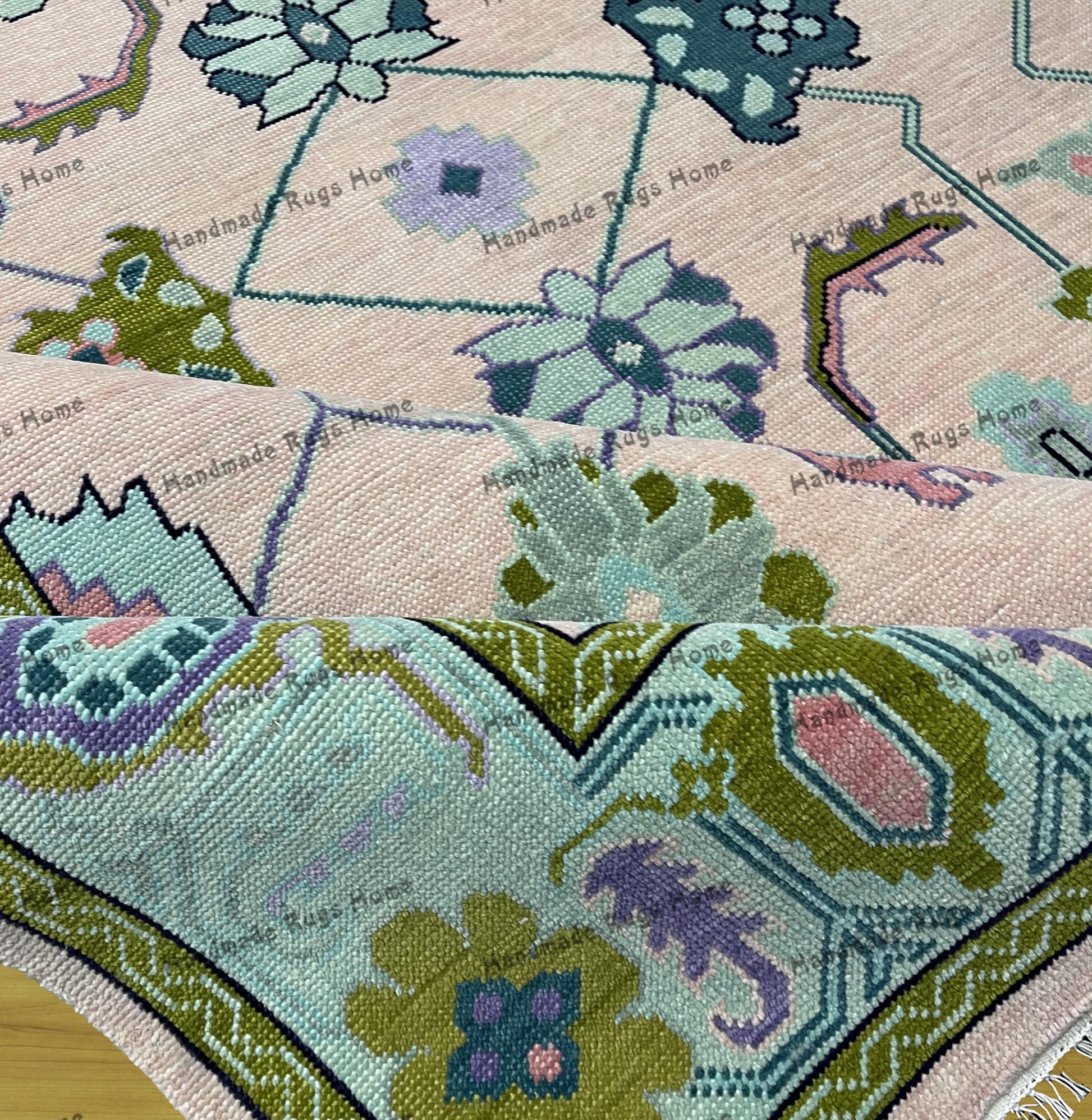 Close-up of a pastel green and pink Turkish rug with intricate designs.
