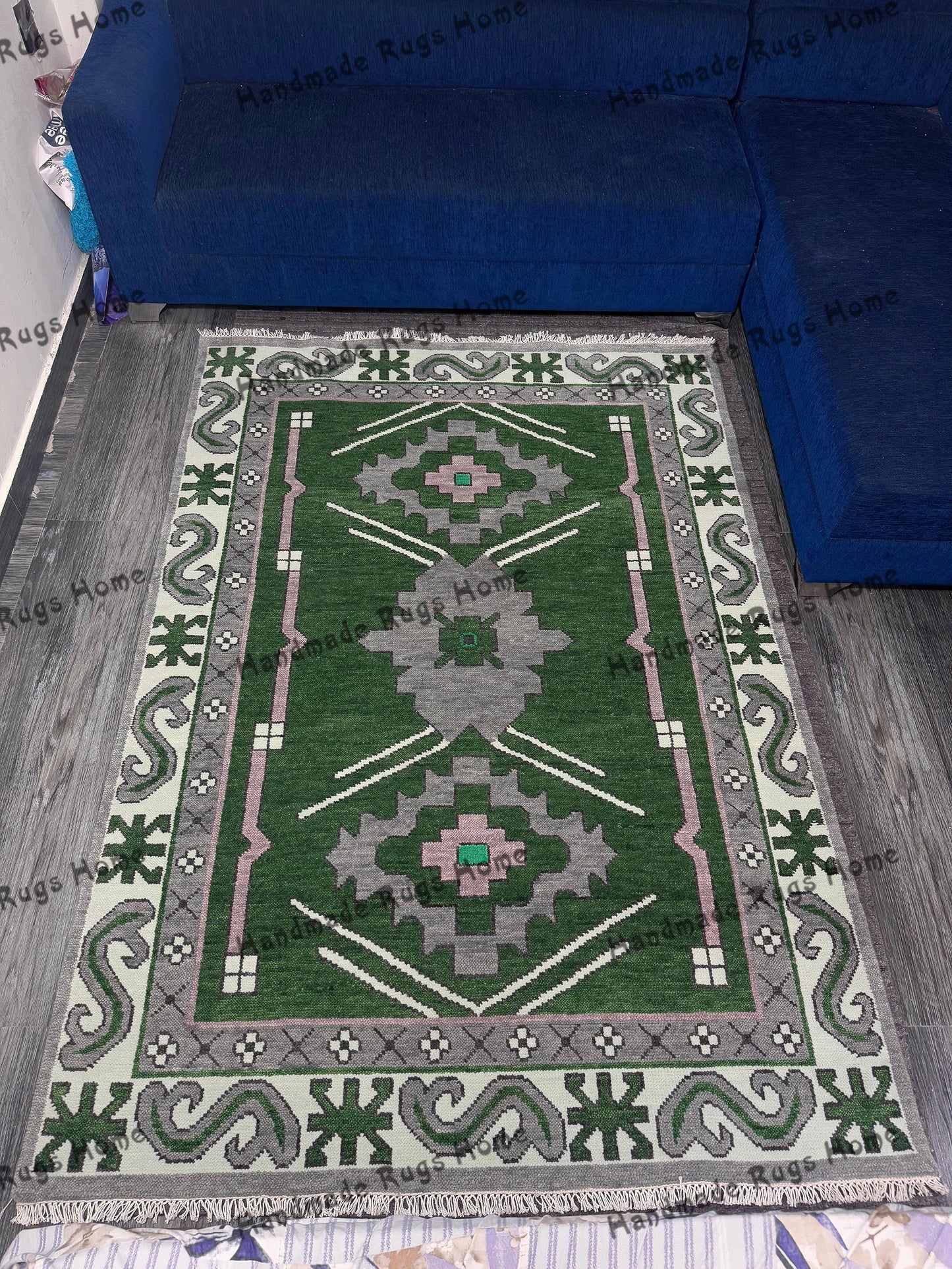 Elegant green and pink wool rug placed under a dark green sectional sofa.