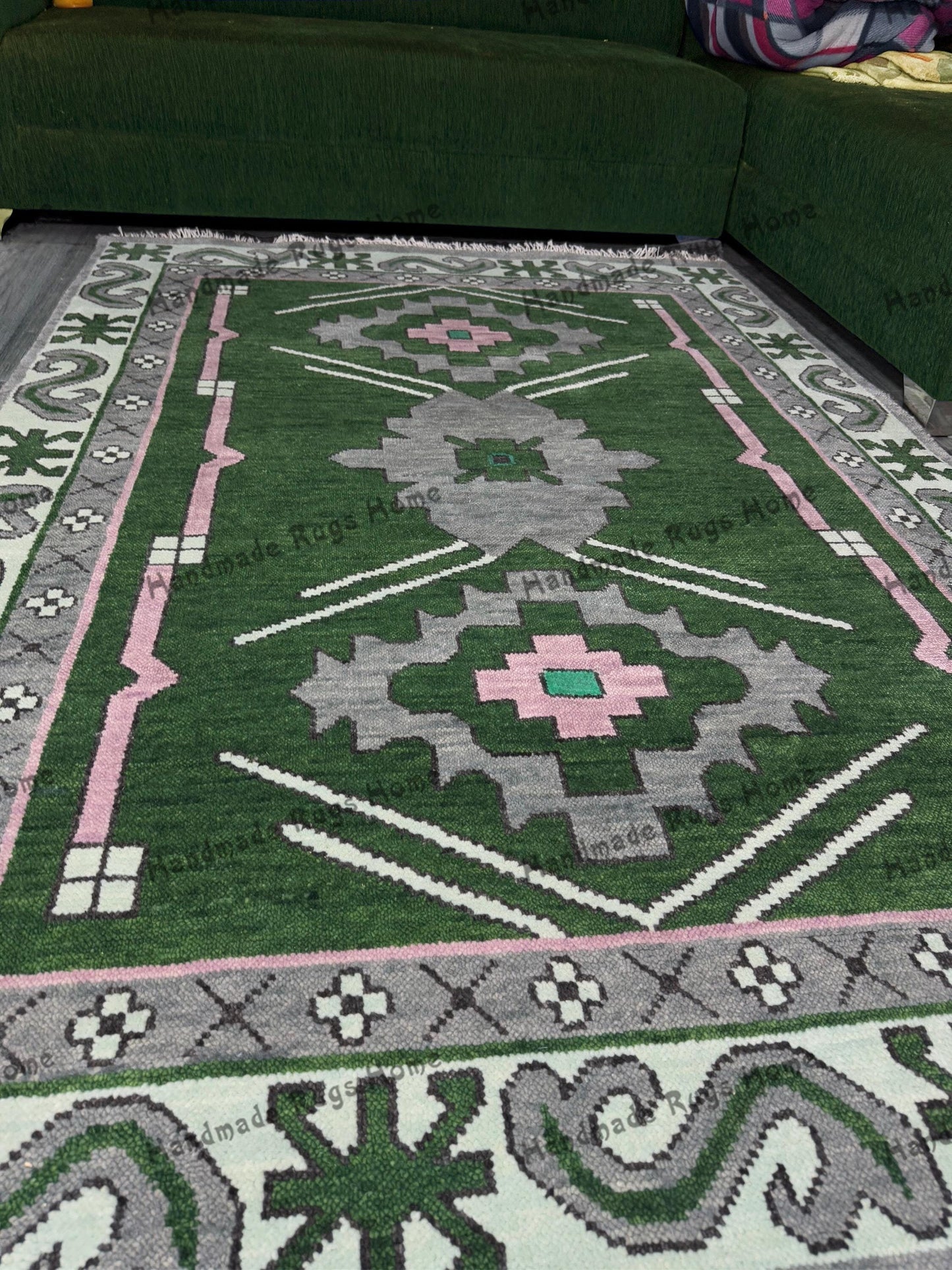 Handmade Oushak rug with green, pink, and grey geometric patterns in a cozy living room.