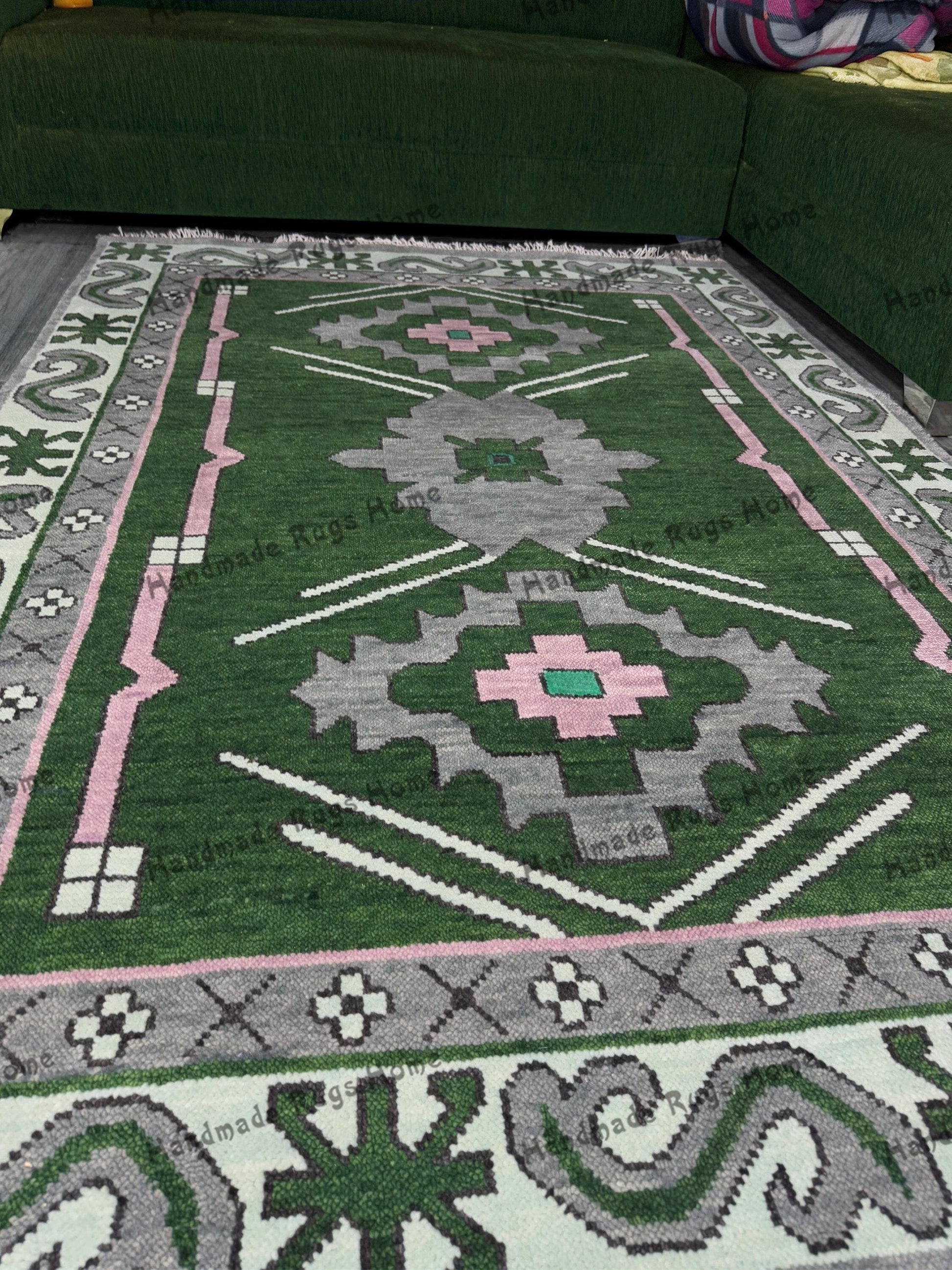 Handmade Oushak rug with green, pink, and grey geometric patterns in a cozy living room.