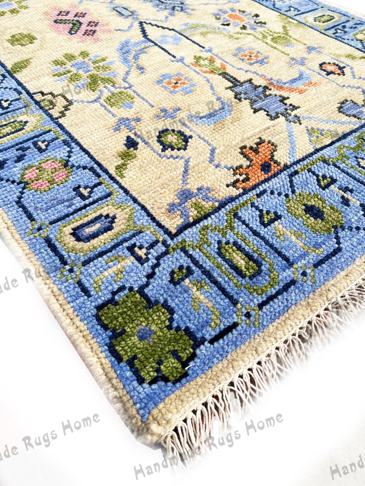 May include: A close-up of a blue and cream colored rug with a floral pattern. The rug has a fringe border and is made of wool. The rug is handmade and is a beautiful example of traditional rug making.