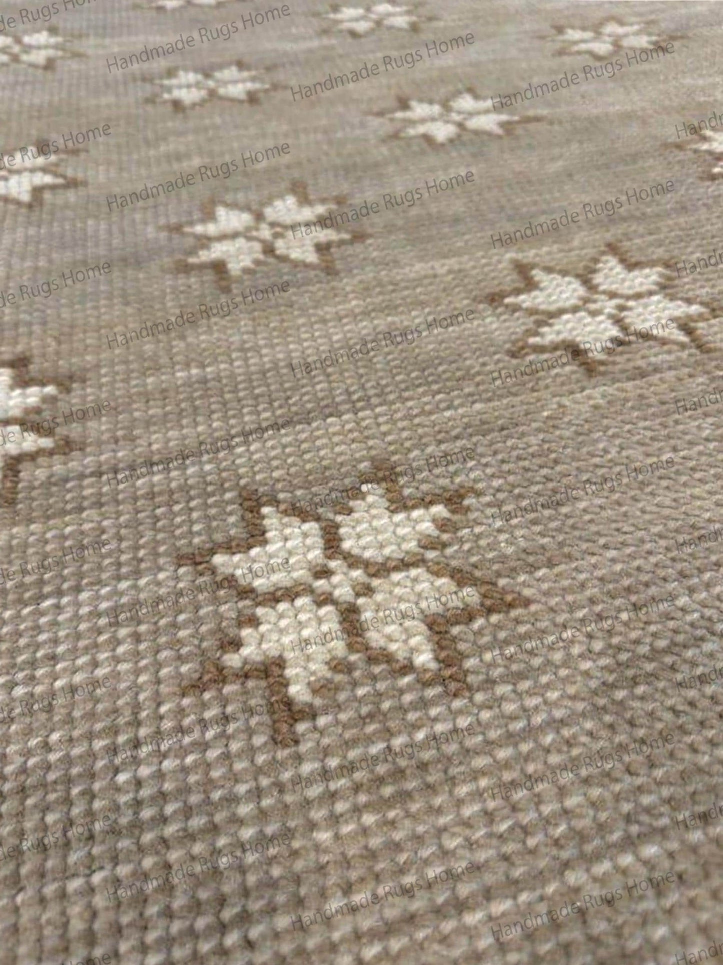 Hand-knotted wool rug in beige with a repeating cream and tan star pattern.