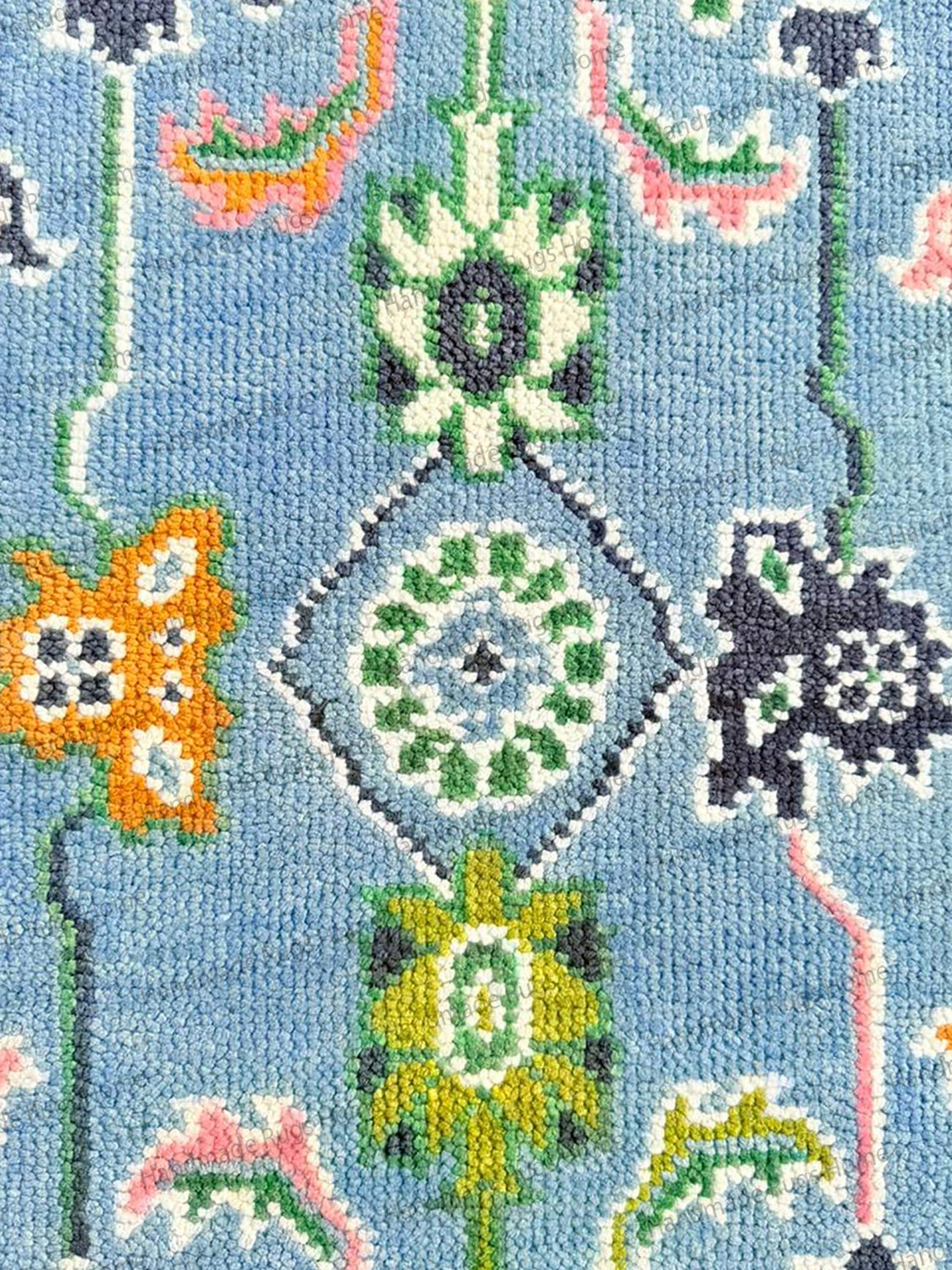 Hand-loomed rectangular rug with dark green and navy border. Statement blue floor piece with oversized floral elements.