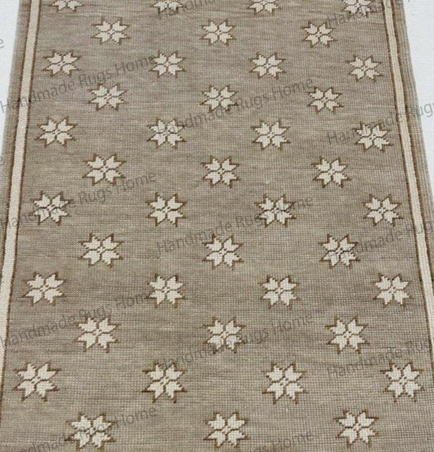 Oushak-style wool carpet with a creamy white star repeating throughout the muted tan pile.