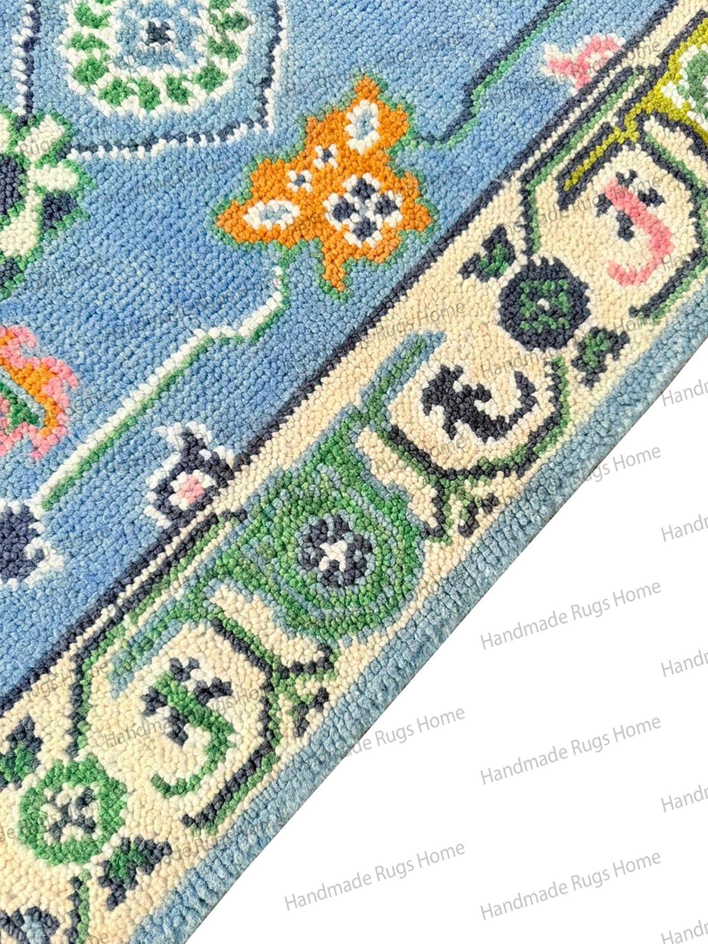 Artisanal handmade wool area textile, featuring an abstract floral pattern and an elegant thick border in blue, green, and blush tones.
