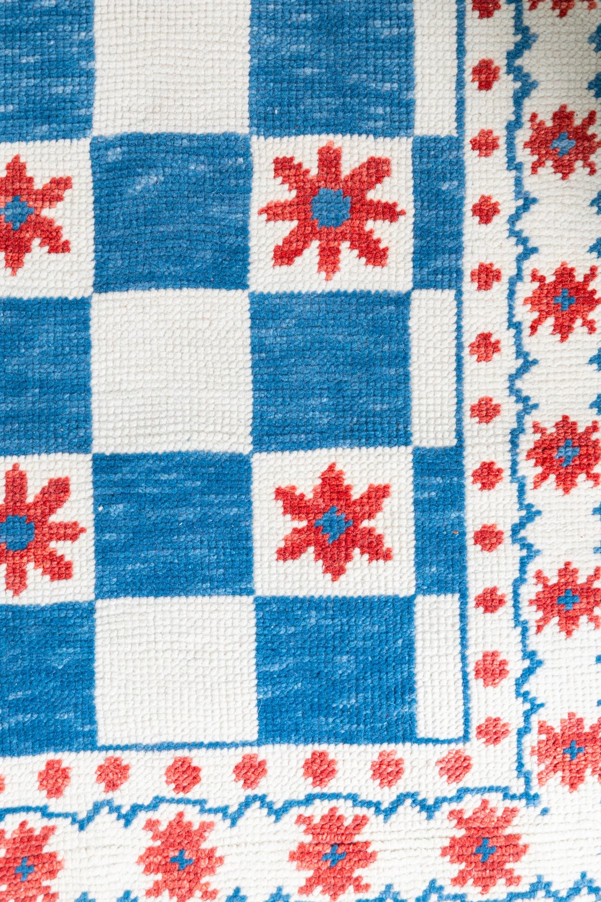Close-up of blue red and ivory Modern Oushak rug showing checkerboard blocks and repeating floral motifs