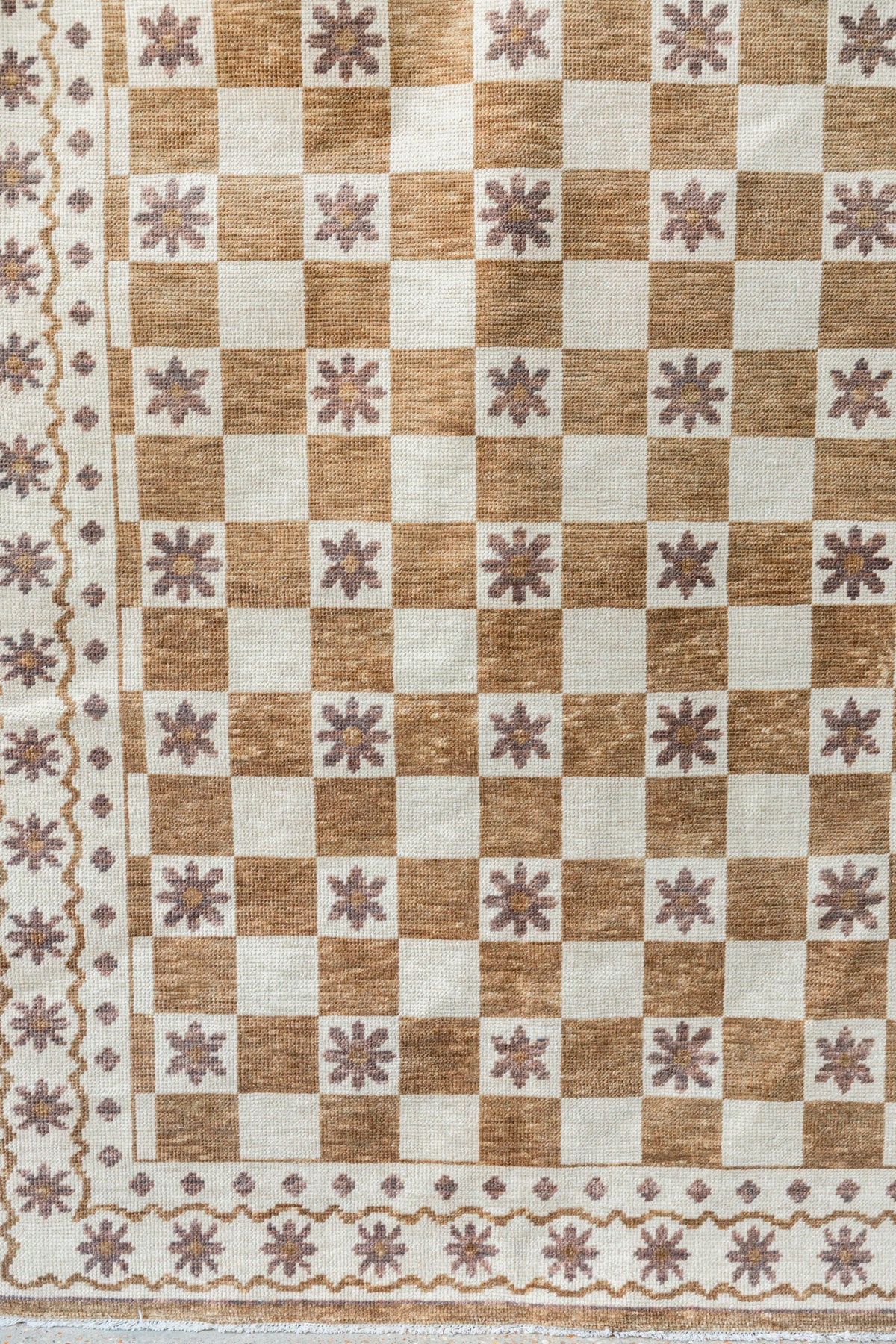 Close-up of brown and ivory Modern Oushak rug showing checkerboard blocks, floral motifs and decorative border
